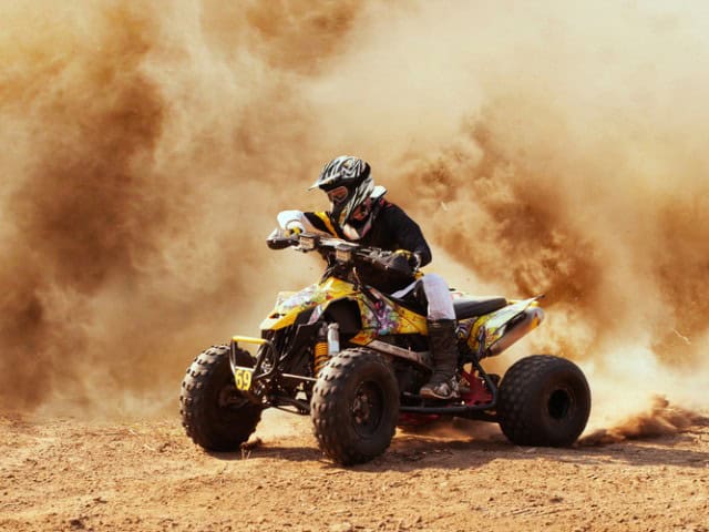 A picture of someone riding a quad bike in desert.