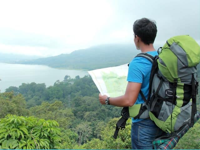 A picture of a man using a physical map while traveling and backpacking.