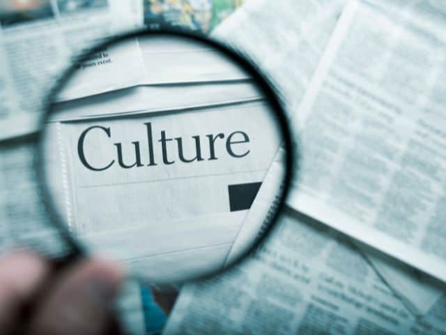 A picture of a person holding a magnifying glass on the word "culture" to indicate understanding cultures better.