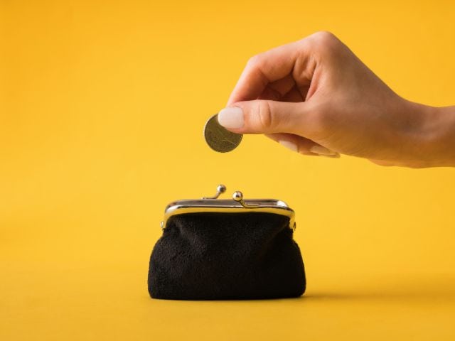 A picture of a person putting a coin into a purse to indicate the idea of saving money.