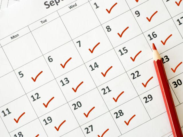 A picture of a calendar filled with red right marks and it has a coloring pen on top of it.