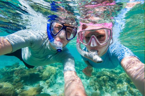 A picture of a couple taking a selfie while snorkeling in the ocean.