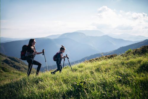 A picture of a mother and her daughter hiking in mountains during morning.