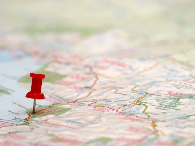 A picture of a red pin stuck into a spot on a map to represent slow travel destinations.