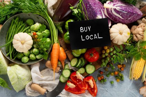 A picture of several kinds of organic food with the words "Buy Local" written on a black sign.