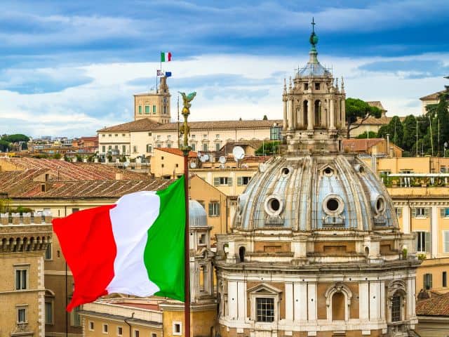 A picture of Santa Maria di Loreto church in Italy with the Italian flag raised in front of it.