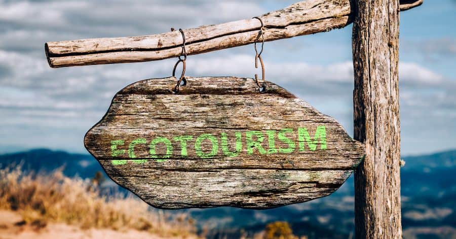 A picture of the word ecotourism written in green on a wooden sign.