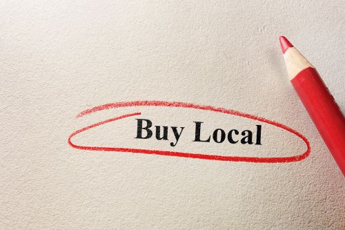 A picture of the words "Buy Local" written on a textured paper in black and circled in red.