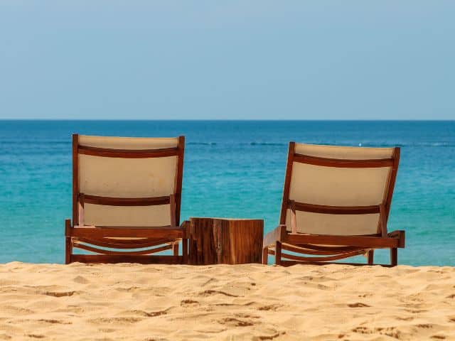 A picture of two empty beach chairs on an empty beach with no crowd.