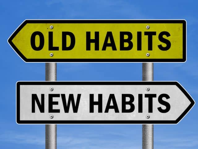 A picture of two signs pointing in different directions with the words "OLD HABITS" written on one and "NEW HABITS" written on the other one similar to trying to change habits with slow travel.