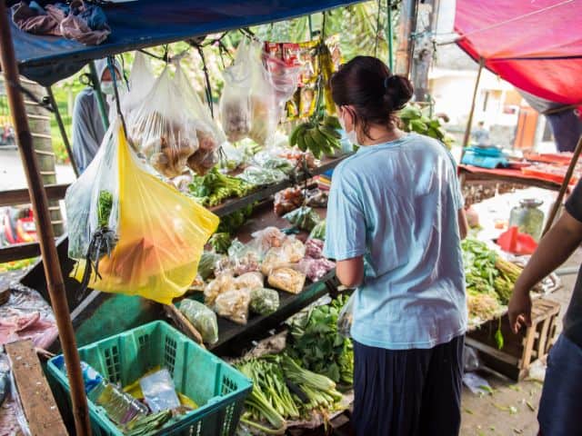 A picture of a woman buying products from a local shop in Indonesia.