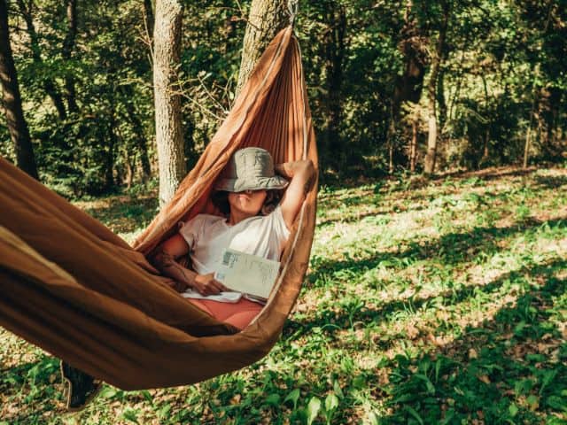 A picture of a woman relaxing outdoors while on a hammock.