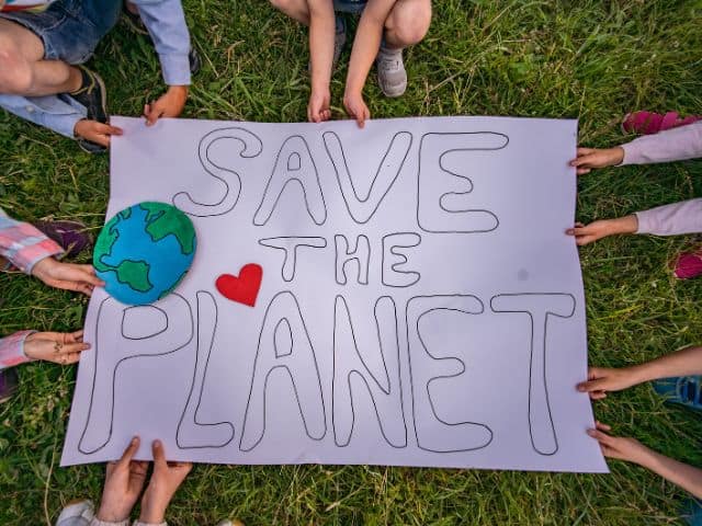 A picture of several people holding a sign saying "save the planet"