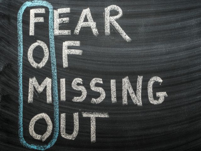 A picture of the sentence "FEAR OF MISSING OUT" written on a black board.