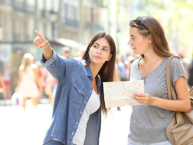 A picture of a female traveler asking a woman for directions.