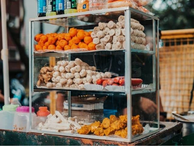 A picture of a food cart placed in a street.