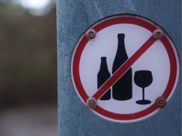 A picture of a no alcohol sign on a grey board with a blurred background.