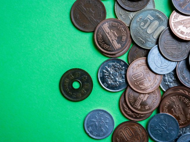 A picture of different kinds of coins placed on a green background.