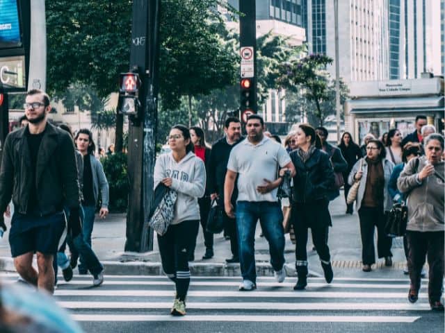 A picture of several people crossing a street together.