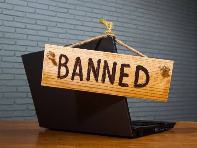 A picture of the word "banned" placed on a wooden sign placed on a laptop.