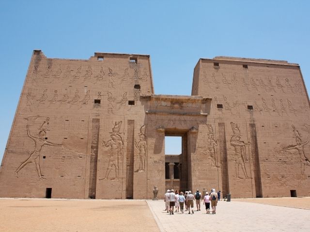 A picture outside of Horus Temple in Egypt with people walking toward it.