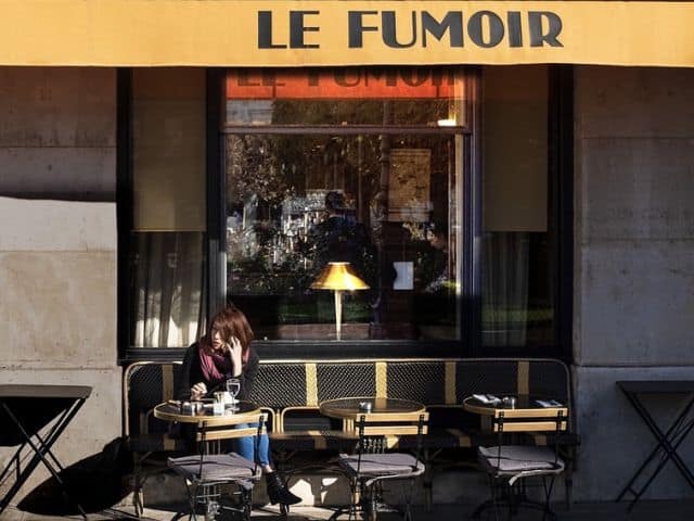 A picture of a woman sitting outside of Le Fumoir restaurant in Paris, France.