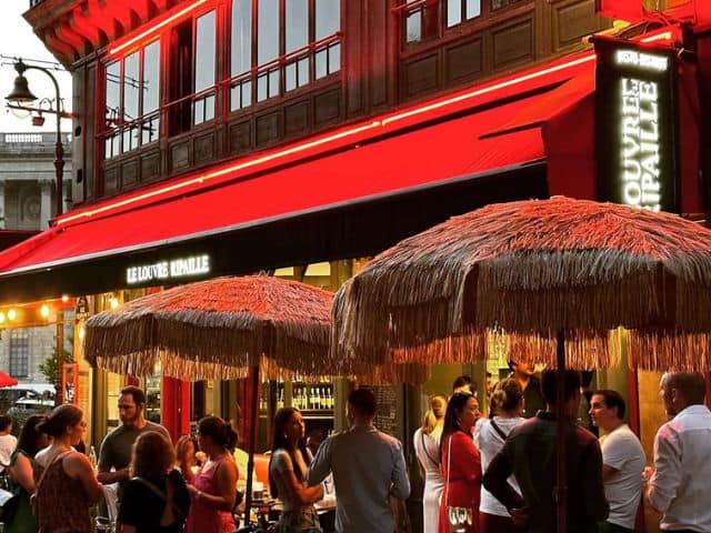 A picture of a group of people standing outside of Le Louvre Ripaille restaurant in Paris, France.