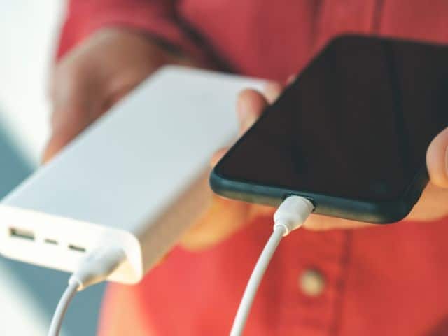 A picture of someone using a power bank to charge their phone.