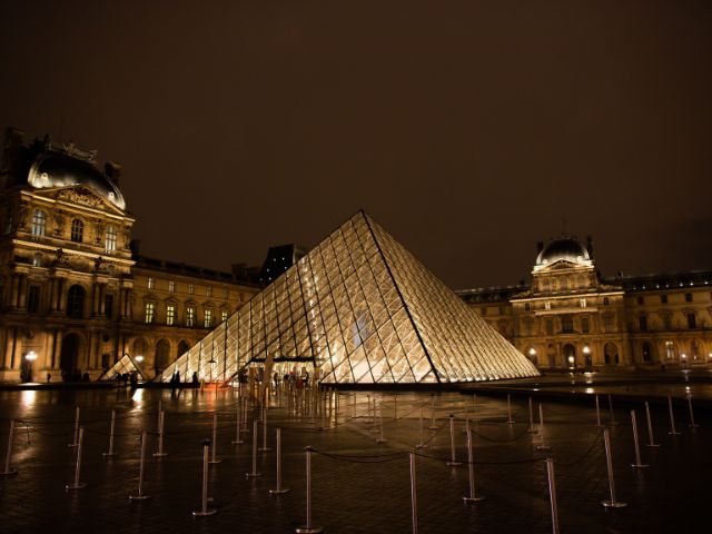 A picture outside of the Louvre Museum during the night.