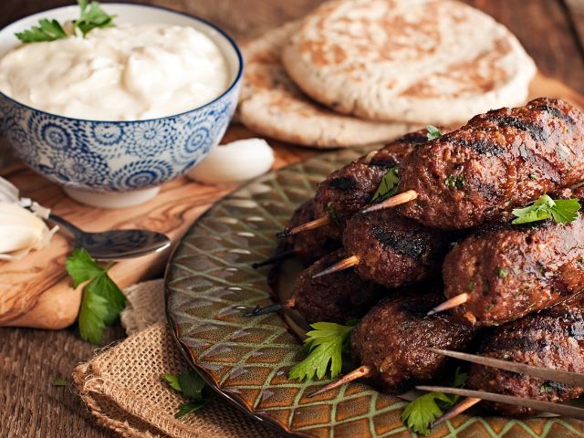 A picture of a kebab and kofta plate with pita bread in the background.