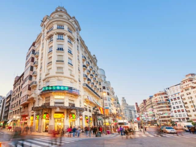 A picture of people crossing the street in downtown Valencia in Spain.