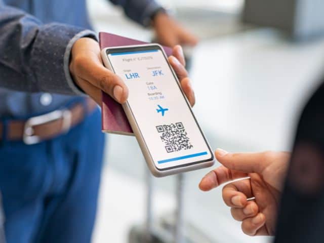 A picture of a man showing a flight attendant his digital boarding ticket.