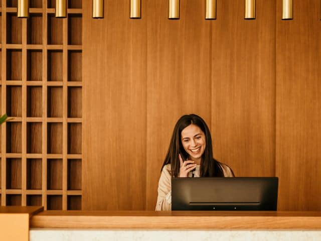 A picture of a hotel receptionist answering a phone.