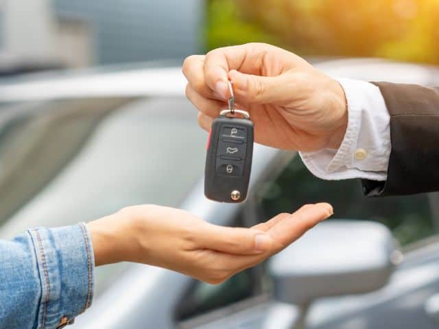 A picture of a man handing a woman a car key.