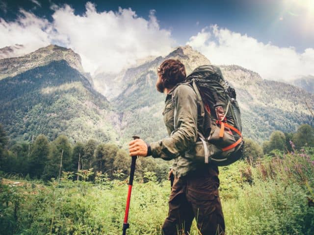 A picture of a man hiking in some mountains. sustainable travel destinations.