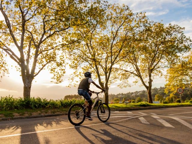 A picture of a man riding a bicycle on a road. sustainable travel destinations. 