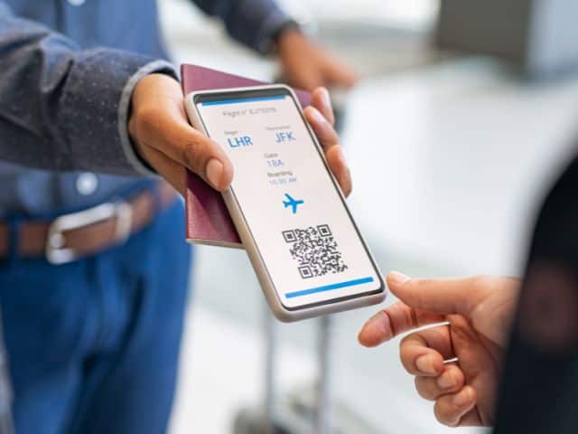 A picture of a man showing a digital flight ticket on his phone. sustainable travel destinations.