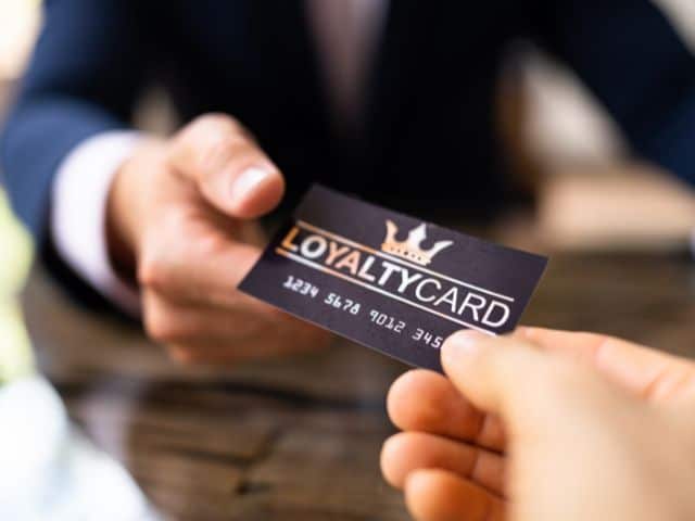 A picture of a person handing another a card with the words "loyalty card" on it.