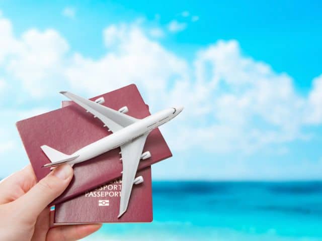 A picture of someone holding a passport and a small airplane in one hand.