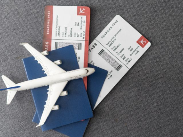 A picture of two plane tickets and two passports with a toy plane on top of them.