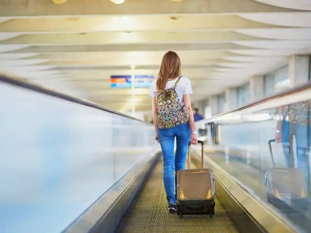 A picture of a woman walking with a carry-on bag.