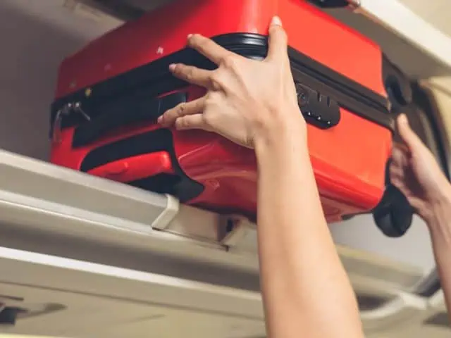 A picture of someone putting a bag in an airplane.